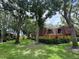 Exterior view of townhome with red tile roof, green grass and many trees at 2716 11Th Ct, Palm Harbor, FL 34684