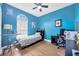 Vibrant bedroom with blue walls, wood floors, arched window, and ceiling fan at 31241 Kirkshire Ct, Wesley Chapel, FL 33543