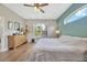 Comfortable main bedroom with wood floors, ceiling fan, dresser and large window views at 31241 Kirkshire Ct, Wesley Chapel, FL 33543