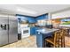 Charming kitchen with blue cabinets, stainless steel refrigerator, and breakfast bar seating at 3743 Cherrywood Dr, Holiday, FL 34691