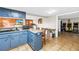 Kitchen featuring blue cabinetry, a breakfast bar, and access to the recreation and dining areas at 3743 Cherrywood Dr, Holiday, FL 34691