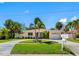 Charming single-story home featuring a circular driveway, well-maintained lawn, and mature palm trees at 429 87Th Ave, St Pete Beach, FL 33706