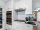 Kitchen features double ovens, stainless hood vent, and black cooktop on white cabinets at 429 87Th Ave, St Pete Beach, FL 33706