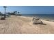 Sandy beach with views of the ocean, featuring picnic shelters and distant waterfront homes at 5133 Glenn Dr, New Port Richey, FL 34652