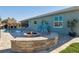 Backyard featuring a custom stone fire pit, pool, tiki hut, outdoor seating, and well-manicured lawn at 5133 Glenn Dr, New Port Richey, FL 34652