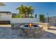 Backyard fire pit area with stone surround, seating, and palm trees at 5133 Glenn Dr, New Port Richey, FL 34652