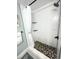 Modern shower with white tiles, pebble floor, and black fixtures providing a spa-like experience at 5133 Glenn Dr, New Port Richey, FL 34652