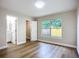 A bedroom with light paint, wood-look flooring, a window with curtains, and two doors at 6511 3Rd Ne Ave, Bradenton, FL 34208