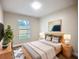 A cozy bedroom features a bed with end tables, a plant, artwork, and a large window at 6511 3Rd Ne Ave, Bradenton, FL 34208