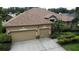 Tan home with a two-car garage, concrete driveway, and well-manicured landscaping surrounding the property at 8731 Tantallon Cir, Tampa, FL 33647