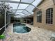 A beautiful screened-in pool with a patterned brick patio surrounded by lush landscaping and large windows at 8731 Tantallon Cir, Tampa, FL 33647