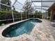A beautiful pool surrounded by lush landscaping with a patterned brick patio and a screened-in enclosure at 8731 Tantallon Cir, Tampa, FL 33647