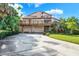 Two-story home with a large deck, two-car garage, and a spacious driveway surrounded by lush greenery at 101 Carlyle Dr, Palm Harbor, FL 34683