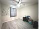 A cozy bedroom features neutral walls and gray vinyl flooring with a ceiling fan and a window with gray curtains at 10221 Carloway Hills Dr, Wimauma, FL 33598