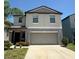 Two-story home featuring a gray exterior, a two-car garage, and a well-manicured lawn with mature landscaping at 10221 Carloway Hills Dr, Wimauma, FL 33598