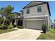 Two-story home with a grey exterior, a two-car garage, a front entrance with columns, and manicured landscaping at 10221 Carloway Hills Dr, Wimauma, FL 33598