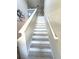 Staircase with white risers, gray treads, a matching white handrail, and neutral colored walls with decorative art at 10221 Carloway Hills Dr, Wimauma, FL 33598
