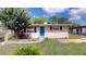 Charming single-story home with a blue front door and a well-maintained lawn and mature trees at 12113 Victory Dr, Hudson, FL 34667