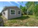 View of the exterior from the side of a home with windows and a yard with a palm tree at 124 E Virginia Ln, Clearwater, FL 33759