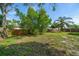 Fenced backyard with large trees and an open grassy area at 124 E Virginia Ln, Clearwater, FL 33759
