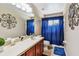 Bathroom with wood cabinets, light countertops, a mirror, and a blue shower curtain at 12915 Carlington Ln, Riverview, FL 33579
