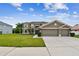 Home exterior showcasing lush landscaping, a well-kept lawn, and an attached two-car garage at 12915 Carlington Ln, Riverview, FL 33579