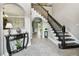 Grand foyer featuring a staircase with dark wood railing, gray floors, console table and arched doorways at 12915 Carlington Ln, Riverview, FL 33579