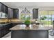 Stylish kitchen featuring dark cabinetry, granite countertops, and views of the outdoor patio dining area at 12915 Carlington Ln, Riverview, FL 33579