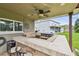 Covered outdoor kitchen features a built-in grill, bar seating, and fan for outdoor entertaining at 12915 Carlington Ln, Riverview, FL 33579