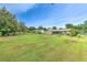 Spacious backyard with lush green grass, mature trees, and views of the neighboring homes at 13311 Omega Ct, Dade City, FL 33525