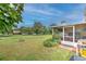 Expansive backyard with lush green lawn, mature trees, a screened-in porch, and space for outdoor enjoyment at 13311 Omega Ct, Dade City, FL 33525