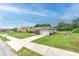 Well-kept home with a spacious driveway, attached garage, and grassy yard on a sunny day at 13311 Omega Ct, Dade City, FL 33525