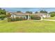 Inviting single-story home with lush green lawn, a blue front door, and manicured bushes at 13311 Omega Ct, Dade City, FL 33525