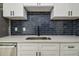 Close-up of the kitchen area showcasing quartz countertops, dark backsplash, and a stainless steel sink at 2017 Waikiki Way, Tampa, FL 33619