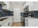 Updated kitchen with white cabinets, stainless steel appliances, dark backsplash, and modern sink at 2017 Waikiki Way, Tampa, FL 33619
