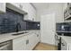 Modern kitchen featuring white cabinets, stainless steel appliances, dark backsplash, and a functional layout at 2017 Waikiki Way, Tampa, FL 33619