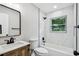 Modern bathroom with white marble tile, wood vanity, black fixtures, and natural light at 2027 Balfour Cir, Tampa, FL 33619