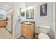 Cozy bathroom with wood cabinets, granite countertop, toilet, and a view of the kitchen through the doorway at 2513 Martucci Rd, Seffner, FL 33584
