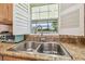 A double basin stainless steel sink with granite countertop and garden window with white shutters is featured at 2513 Martucci Rd, Seffner, FL 33584