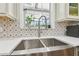 Stainless steel kitchen sink with tile backsplash and a modern faucet with gooseneck design at 2513 Martucci Rd, Seffner, FL 33584