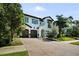 Elegant two-story home featuring a paver driveway, lush landscaping, and a charming architectural design on a sunny day at 4525 W Swann Ave, Tampa, FL 33609