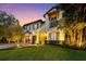 Twilight view of Mediterranean-style home with dark shutters, manicured lawn and lush garden at 4525 W Swann Ave, Tampa, FL 33609
