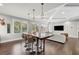 Open-concept living room with dining area featuring a large wood table, modern lighting, and backyard views at 4525 W Swann Ave, Tampa, FL 33609