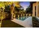A serene backyard pool area surrounded by illuminated landscaping for a tranquil evening ambiance at 4525 W Swann Ave, Tampa, FL 33609