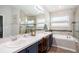 Bathroom with dual sinks, a bathtub, and a glass-enclosed shower featuring neutral tile and ample natural light at 4738 Bloom Dr, Plant City, FL 33566