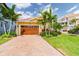 Charming home with a well-manicured lawn, brick driveway, and a beautiful wood garage door surrounded by palm trees at 539 Treviso Dr, Apollo Beach, FL 33572