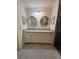 Bathroom features dual sinks, granite counters, round mirrors, and white cabinets at 5720 Palmer Cir # 102, Bradenton, FL 34211