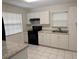 Well-lit kitchen with ample white cabinets, black appliances, and tiled flooring at 6427 2Nd S Ave, St Petersburg, FL 33707