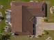 An aerial view of a home with a large brown tile roof, a screened in porch, and surrounded by a green lawn and landscaping at 702 Plumbrook Rd, Sun City Center, FL 33573