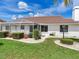 Well-manicured backyard with a screen enclosed patio, lush grass, and decorative landscaping at 702 Plumbrook Rd, Sun City Center, FL 33573